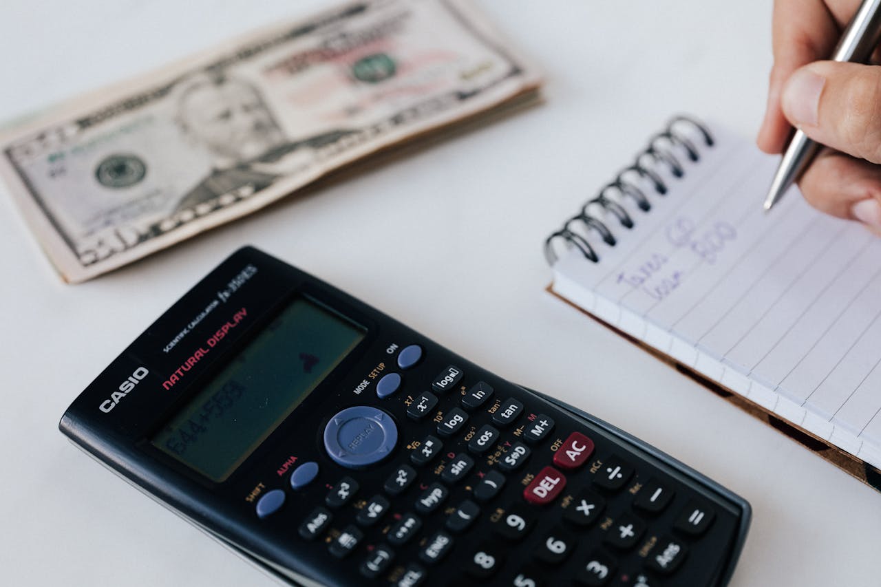 Crop unrecognizable accountant counting savings using notebook and calculator